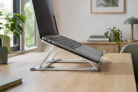 Support pliable argenté à six angles tenant un ordinateur portable sur un bureau en bois clair.