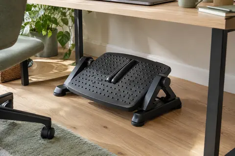 Repose-pieds réglable en plastique avec picots et rouleaux, installé sous un bureau de télétravail.
