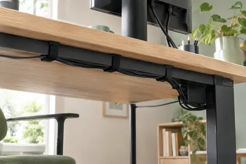 Bandes noires réutilisables regroupant les câbles sous un bureau en bois clair