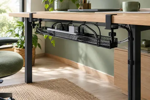Plateau métallique en maille fixé sous un bureau, avec multiprise et câbles rangés et accessibles.